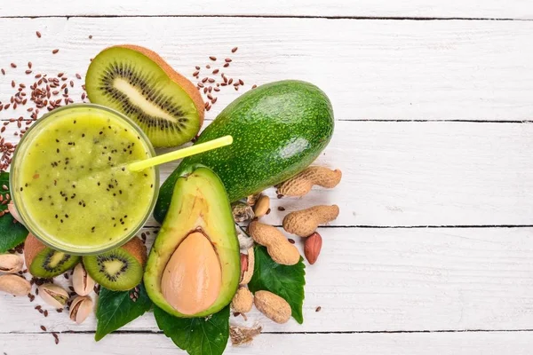 Kiwi smoothie and avocado with flaxseed and nuts. On a wooden background. Top view. Free space for your text.