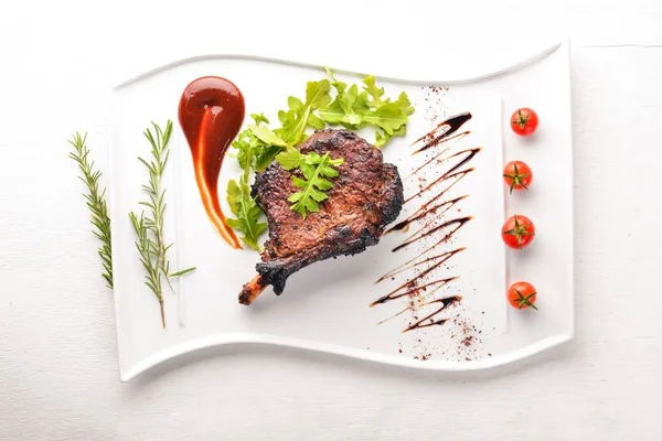 Steak on a bone with tomatoes and a hazelnut. Steak Fiorentino. On a wooden background. Free space for your text. Top view.