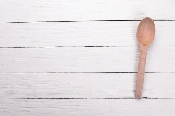A wooden spoon on a white wooden background. Top view. Copy space.