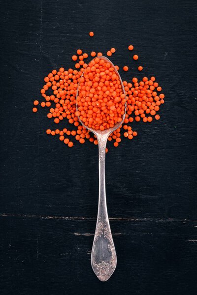 Оранжевая чечевица в ложке. На деревянном фоне. Вид сверху. Копирование пространства
.