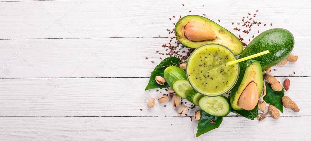 Smoothie with avocado and cucumber with flaxseed and nuts. On a wooden background. Top view. Free space for your text.
