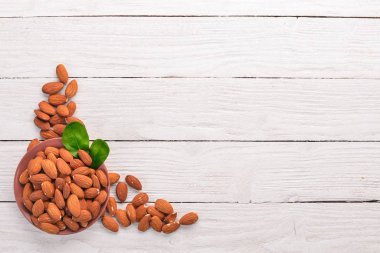 Badem fındık Beyaz ahşap zemin üzerinde. Sağlıklı aperatifler. Üstten Görünüm. Metin için boş alan.