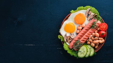 İngiliz kahvaltısı. Kızarmış yumurta, sosis, pastırma, fasulye, tost, domates, kahve fincanı taştan masada. Metin alanı olan Üstten Görünüm