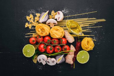 Bir makarna, erişte, makarna, tagliatelle, fettuccine, dizi Farfalle. İtalyan yemek, taze sebze ve baharat. Siyah ahşap arka plan üzerinde. Üstten Görünüm. Kopya alanı.