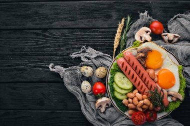 Tam İngiliz kahvaltısı kızarmış yumurta, sosis, fasulye, tost ve kahve kopya alan arka plan üzerinde. Siyah bir ahşap arka plan üzerinde.