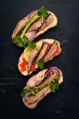 Hamsi ve havyar, soğan ve maydanoz, ahşap arka plan üzerinde sandviç kümesi. Üstten Görünüm. Kopya alanı.