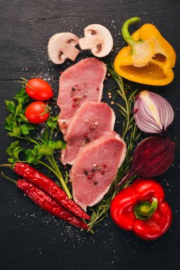 Taze sebze ve biberiye ve baharat siyah ahşap zemin sığır eti biftek. Üstten Görünüm. Metin için boş alan.