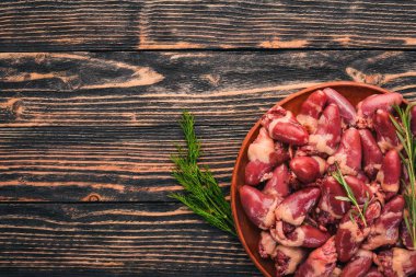 Çiğ tavuk kupa rosemary ile yemek pişirmek için hazır plaka üzerinde ve üzerinde baharat siyah ahşap arka plan. Üstten Görünüm. Metin için boş alan.