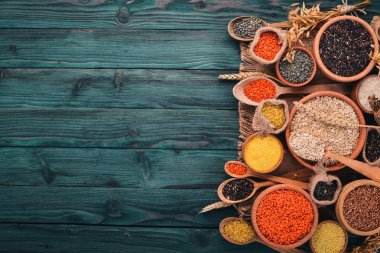 Kabuğu çıkarılmış tane ve tahıl kümesi. Buğday, mercimek, pirinç, darı, arpa, Mısır, siyah pirinç. Mavi ahşap arka plan üzerinde. Üstten Görünüm. Kopya alanı.