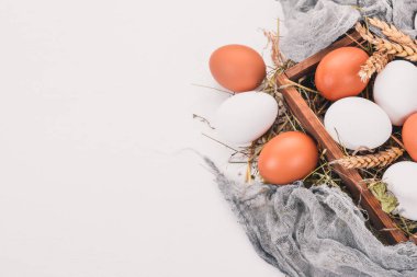 Tavuk ahşap sepet içinde çiğ yumurta. Beyaz ahşap zemin üzerinde. Üstten Görünüm. Kopya alanı.
