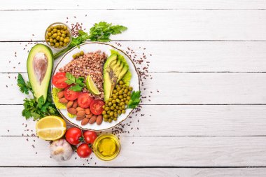 Sağlıklı gıda. Karabuğday, cherry domates, avokado, badem ve yeşil bezelye. Ahşap bir arka plan üzerinde. Üstten Görünüm. Metniniz için boş alan.