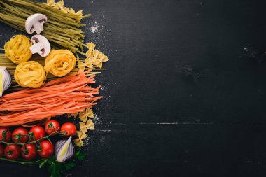 Bir makarna, erişte, makarna, tagliatelle, fettuccine, dizi Farfalle. İtalyan yemek, taze sebze ve baharat. Siyah ahşap arka plan üzerinde. Üstten Görünüm. Kopya alanı.