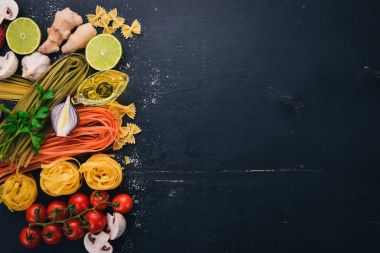 Bir makarna, erişte, makarna, tagliatelle, fettuccine, dizi Farfalle. İtalyan yemek, taze sebze ve baharat. Siyah ahşap arka plan üzerinde. Üstten Görünüm. Kopya alanı.