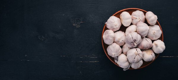 Garlic on a plate. Fresh garlic on a wooden background. Top view. Copy space.