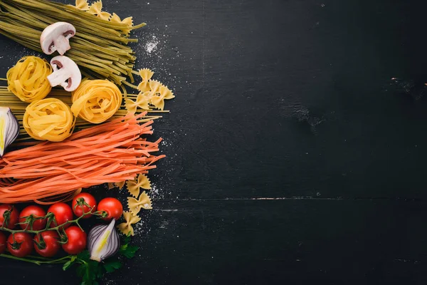 Bir makarna, erişte, makarna, tagliatelle, fettuccine, dizi Farfalle. İtalyan yemek, taze sebze ve baharat. Siyah ahşap arka plan üzerinde. Üstten Görünüm. Kopya alanı.