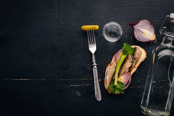 Vodka and a set of sandwiches with sprats, and caviar, onion and parsley, on a wooden background. Top view. Copy space. — Stock Image Vodka Set Sandwiches Sprats Caviar Onion Parsley Wooden Background Top Stock Image