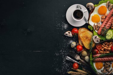 İngiliz kahvaltısı. Kızarmış yumurta, sosis, pastırma, fasulye, tost, domates, kahve fincanı taştan masada. Metin alanı olan Üstten Görünüm