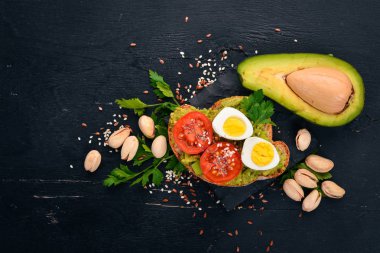 Bıldırcın yumurtası, avokado, domates ve antep fıstığı ile sandviç. Ahşap bir arka plan üzerinde. Üstten Görünüm. Metniniz için boş alan.