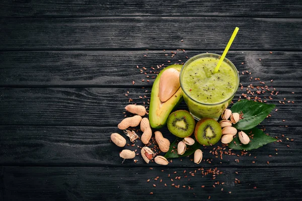 Kiwi smoothie and avocado with flaxseed and nuts. On a wooden background. Top view. Free space for your text.