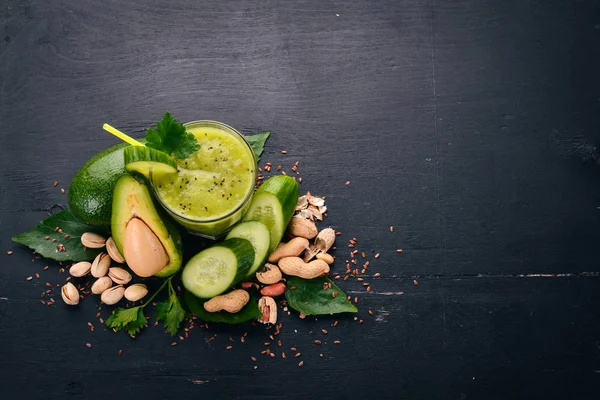 Smoothie with avocado and cucumber with flaxseed and nuts. On a wooden background. Top view. Free space for your text.