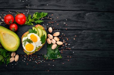 Bıldırcın yumurta, salatalık ve antep fıstığı ile avokado sandviç. Ahşap bir arka plan üzerinde. Üstten Görünüm. Metniniz için boş alan.