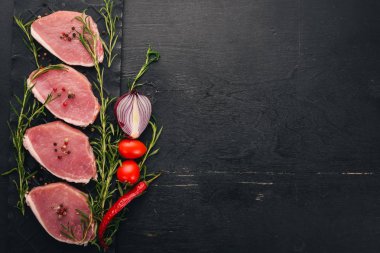 Çiğ et. Biberiye ve baharat siyah ahşap zemin sığır eti biftek. Üstten Görünüm. Metin için boş alan.