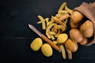 Çiğ patates siyah ahşap zemin. Yemek. Metin için özgür yer. Üstten Görünüm.