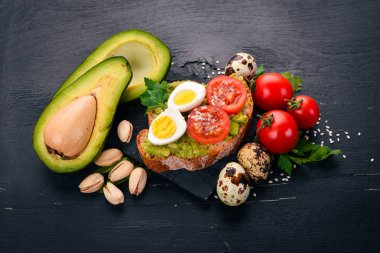 Bıldırcın yumurtası, avokado, domates ve antep fıstığı ile sandviç. Ahşap bir arka plan üzerinde. Üstten Görünüm. Metniniz için boş alan.