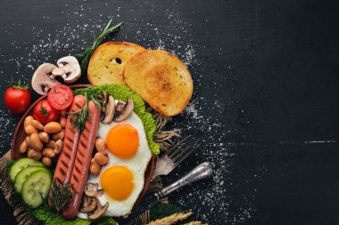 İngiliz kahvaltısı. Kızarmış yumurta, sosis, pastırma, fasulye, tost, domates, kahve fincanı taştan masada. Metin alanı olan Üstten Görünüm