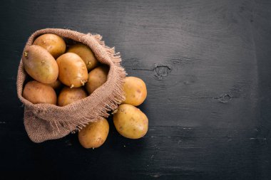 Çiğ patates siyah ahşap zemin. Yemek. Metin için özgür yer. Üstten Görünüm.