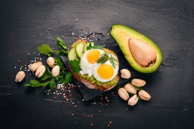 Bıldırcın yumurta, salatalık ve antep fıstığı ile avokado sandviç. Ahşap bir arka plan üzerinde. Üstten Görünüm. Metniniz için boş alan.