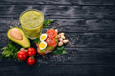 Avokado, yumurta, domates ve antep fıstığı ile sandviç. Kivi suyu. Ahşap bir arka plan üzerinde. Üstten Görünüm. Metniniz için boş alan.