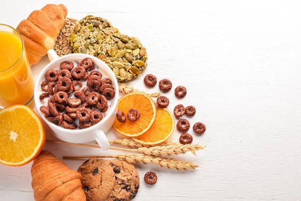 Fitness breakfast, muesli, milk, fruits, nuts and seeds, on a wooden surface. Top view. Free space for text.