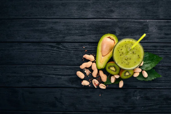 Kiwi smoothie and avocado with flaxseed and nuts. On a wooden background. Top view. Free space for your text.