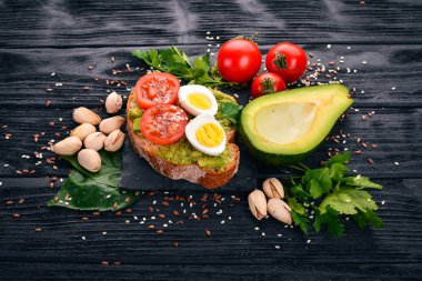 Bıldırcın yumurtası, avokado, domates ve antep fıstığı ile sandviç. Ahşap bir arka plan üzerinde. Üstten Görünüm. Metniniz için boş alan.