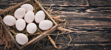 Tavuk ahşap sepet içinde çiğ yumurta. Ahşap bir arka plan üzerinde. Üstten Görünüm. Kopya alanı.