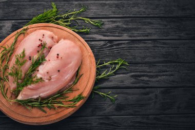 Biberiye ve baharat siyah ahşap zemin ile çiğ tavuk göğsü fileto. Üstten Görünüm. Metin için boş alan.