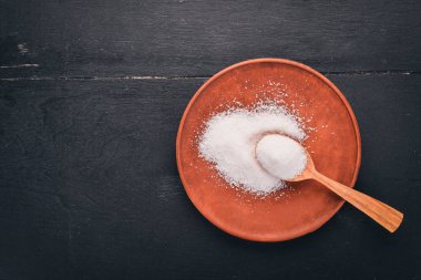 Bir plaka üzerinde bir tahta kaşık tuz. Ahşap bir arka plan üzerinde. Üstten Görünüm. Metin için boş alan.