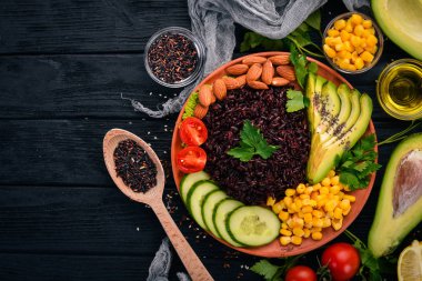 Siyah pirinç, avokado, salatalık, Mısır ve badem. Ahşap bir arka plan üzerinde. Üstten Görünüm. Metniniz için boş alan.