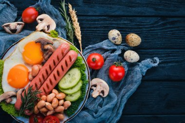 Tam İngiliz kahvaltısı kızarmış yumurta, sosis, fasulye, tost ve kahve kopya alan arka plan üzerinde. Siyah bir ahşap arka plan üzerinde.