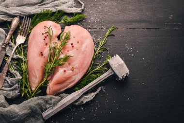 Biberiye ve baharat siyah ahşap zemin ile çiğ tavuk göğsü fileto. Üstten Görünüm. Metin için boş alan.