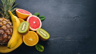 Taze tropikal meyve. Ananas, Hindistan cevizi, kivi, portakal, nar, greyfurt. Ahşap bir arka plan üzerinde. Üstten Görünüm. Metin için boş alan.