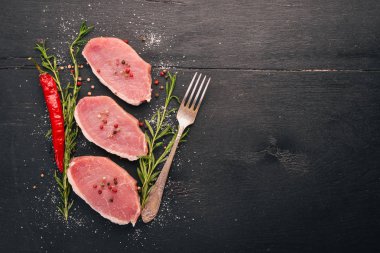 Çiğ et. Biberiye ve baharat siyah ahşap zemin sığır eti biftek. Üstten Görünüm. Metin için boş alan.