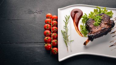 Domates ve bir fındık ile bir kemik biftek. Biftek Fiorentino. Ahşap bir arka plan üzerinde. Metniniz için boş alan. Üstten Görünüm.