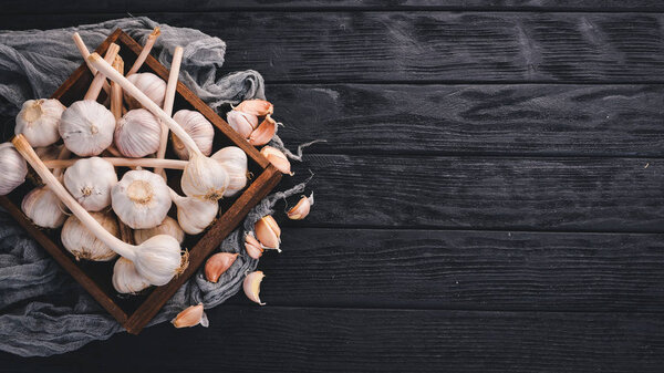 Garlic in a wooden basket. Fresh garlic on a wooden background. Top view. Free space for text.