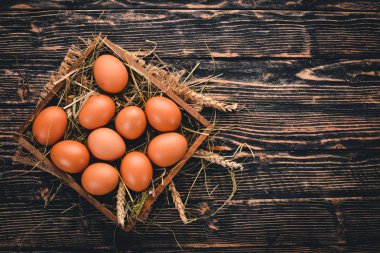 Tavuk ahşap sepet içinde çiğ yumurta. Ahşap bir arka plan üzerinde. Üstten Görünüm. Kopya alanı.
