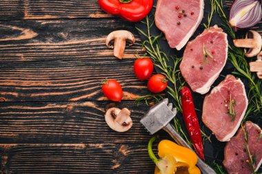 Taze sebze ve biberiye ve baharat siyah ahşap zemin sığır eti biftek. Üstten Görünüm. Metin için boş alan.