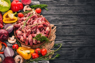 Çiğ tavuk kupa rosemary ile yemek pişirmek için hazır plaka üzerinde ve üzerinde baharat siyah ahşap arka plan. Üstten Görünüm. Metin için boş alan.