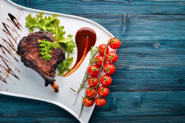 Domates ve bir fındık ile bir kemik biftek. Biftek Fiorentino. Ahşap bir arka plan üzerinde. Metniniz için boş alan. Üstten Görünüm.
