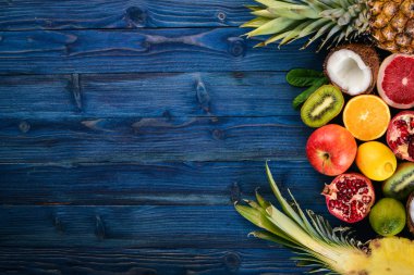 Taze tropikal meyve. Ananas, Hindistan cevizi, kivi, portakal, nar, greyfurt. Ahşap bir arka plan üzerinde. Üstten Görünüm. Metin için boş alan.